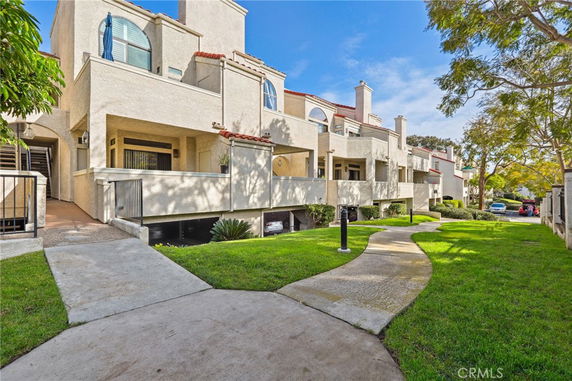 Front view of a multi-unit residential building with balconies and a pathway leading to it.