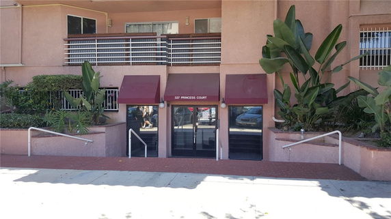 Front view of a building entrance with stairs leading down and red awnings.