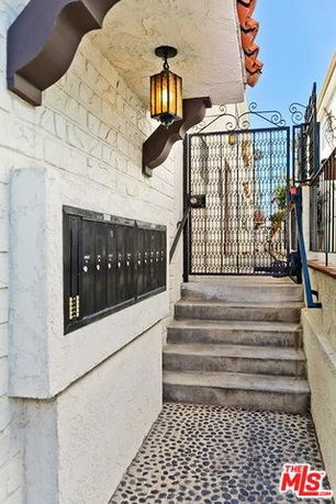 Stairs leading to a gated entrance with mailboxes mounted on a brick wall.