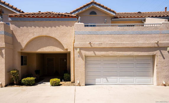 Front view of a two-story house with a double garage and arched entryway.