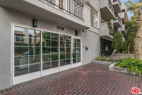 Front view of a building entrance with glass doors and balconies above.