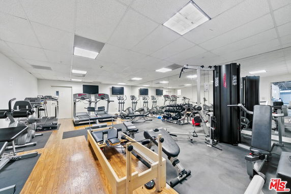 Indoor gym with various exercise equipment and mirrored wall.