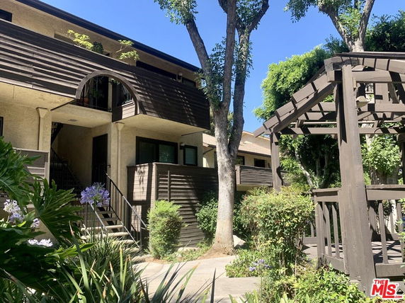 Front view of a multi-story residential building with balconies and wooden siding.