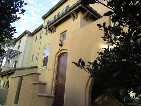 Front view of a multi-story house with arched entrance and light tan exterior.
