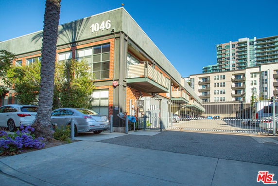 Front view of a multi-story building with large windows and an entrance gate.
