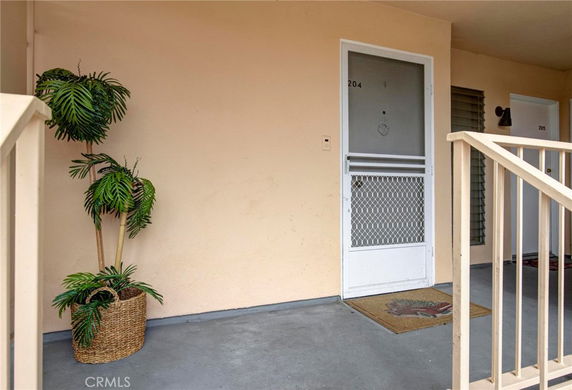 Front view of an entrance with a screen door and a doormat on a small porch area.
