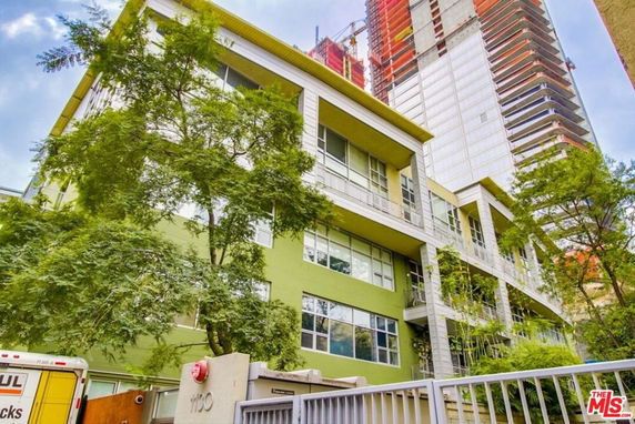 Front view of a multi-story building with green exterior and large windows.