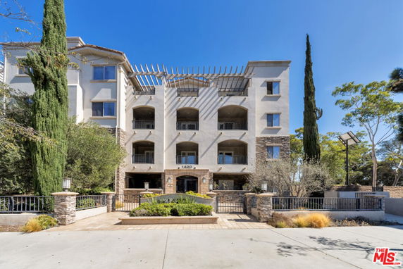 Front view of a multi-story building with balconies and a pergola.