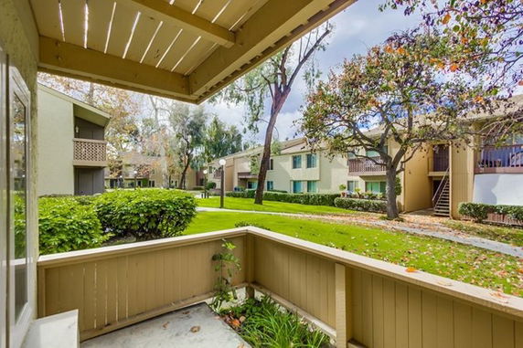 View from a patio overlooking a residential complex with multiple two-story buildings and a grassy area.