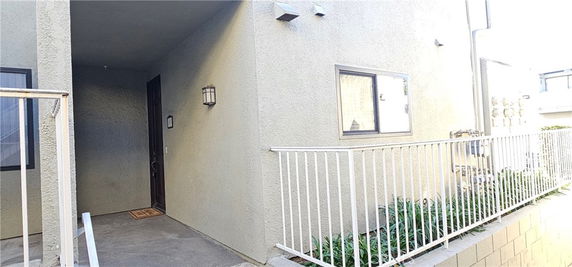 Exterior view of a building entrance with a front door, window, and railing.