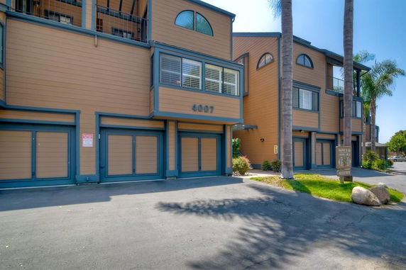 Front view of a multi-story building with garages at the ground level.