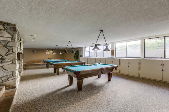 Indoor area with multiple pool tables and large windows.