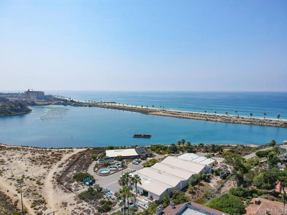 Panoramic view of a coastal area with a body of water and a breakwater extending into the ocean.