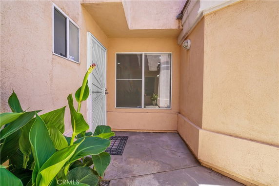 View of a house entrance with a door and window set in a stucco wall.