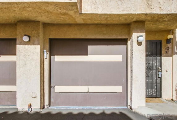 Front view of a building section with a garage and entrance door.