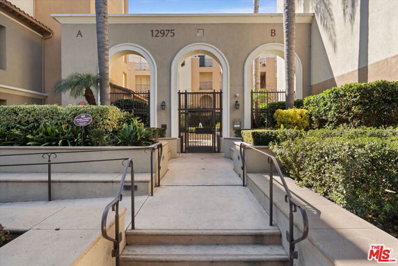 Front view of a building entrance with arched entryways and gates.