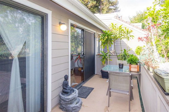 Rooftop area with plants and seating, featuring a sliding glass door and outdoor decor.