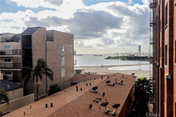 Panoramic view from a building showing rooftops with satellite dishes and a beach with seaside in the background.