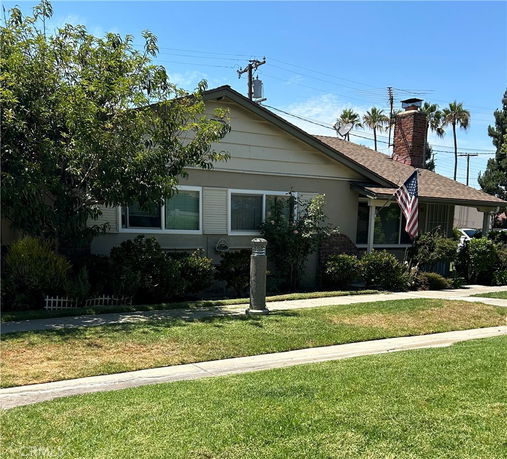 Front view of a single-story house with a chimney and American flag.