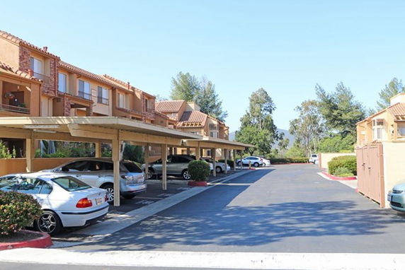 Outdoor parking area with covered spaces in front of a residential building.