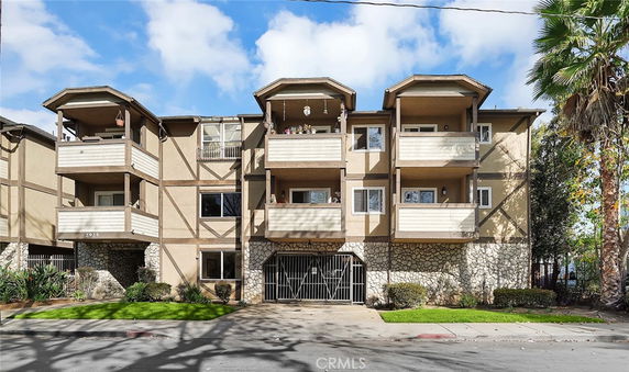 Front view of a multi-story residential building with balconies and stone accents.