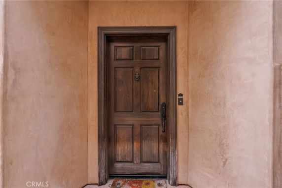 Front view of a wooden door with a knocker, set in a stucco wall.