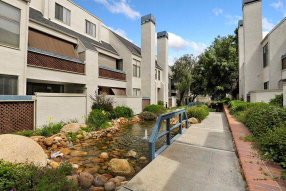 Front view of multi-story residential buildings with a landscaped path and water feature.
