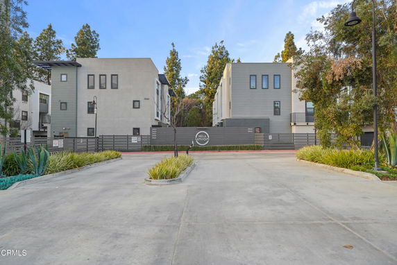 Front view of a modern multi-story residential building with a gated entrance.
