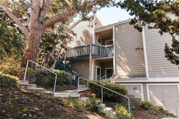 Front view of a multi-story residential building with stairs leading to the entrance.