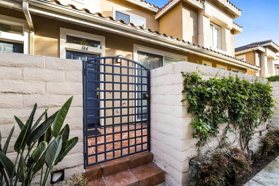 Front view of a two-story house with a gated entrance and tiled pathway.