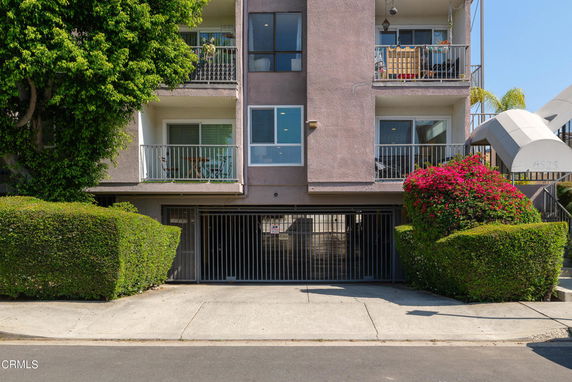 Front view of a multi-unit residential building with balconies and a gated entrance.