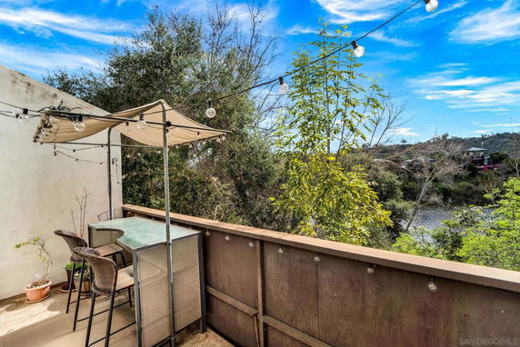 Outdoor area with a small table, chairs, and string lights overlooking a scenic view of trees and hills.