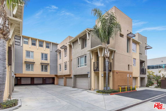 Front view of a multi-story apartment building with garages on the ground level.