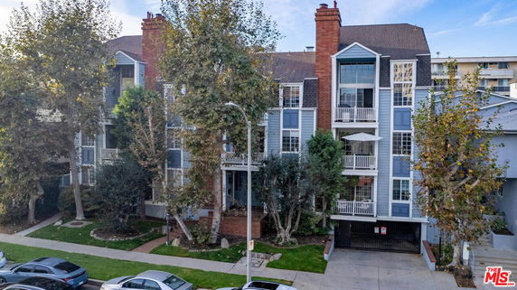 Front view of a multi-story residential building with balconies and brick accents.