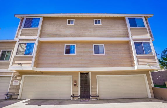 Front view of a three-story building with two garage doors on the ground floor.