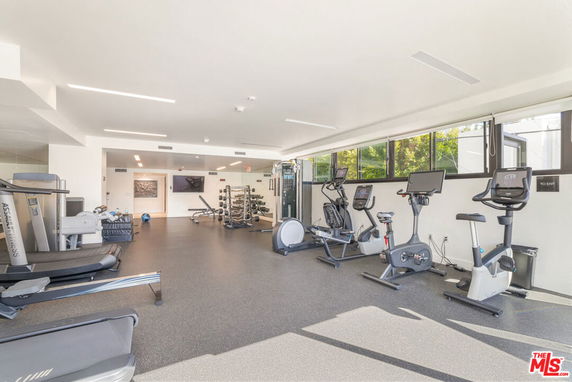 Interior view of a modern gym with exercise equipment and large windows.