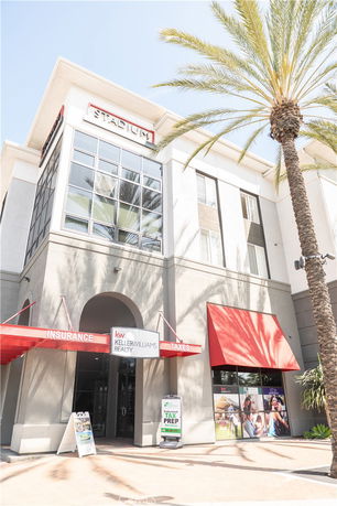Front view of a commercial building with large windows and red awnings.
