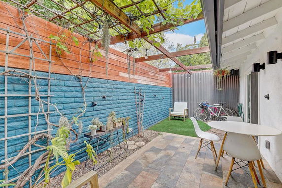 Outdoor patio area with table and chairs, plants, and bicycles.