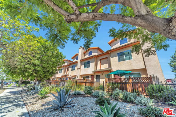 Front view of a multi-story residential building with a landscaped entry.