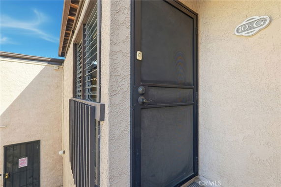Exterior view of a building entrance with a black screen door and window.