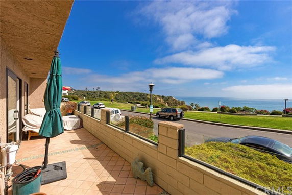 View from a patio overlooking a scenic road and ocean in the distance.