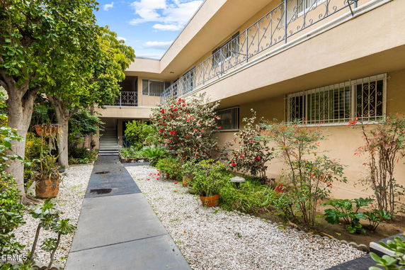 Front view of a two-story building with an open courtyard and garden area.