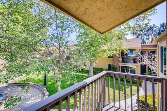 View from a balcony overlooking a courtyard with trees and residential buildings.