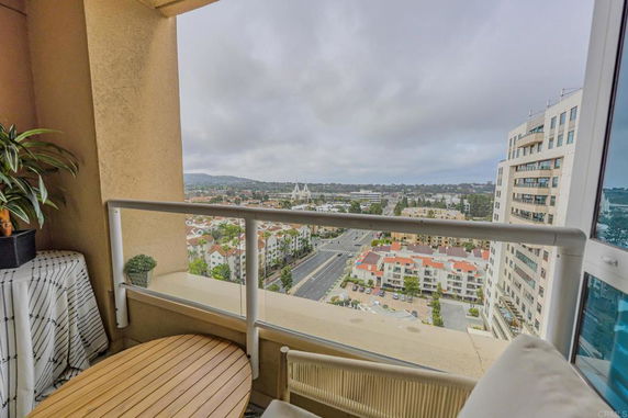 View from a balcony overlooking a cityscape with roads and multiple buildings.