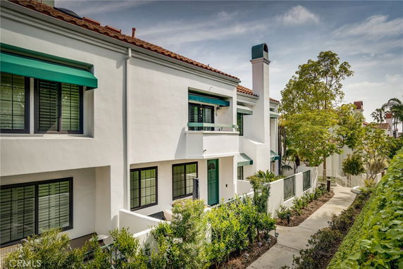 Front view of a two-story house with green awnings and a chimney.