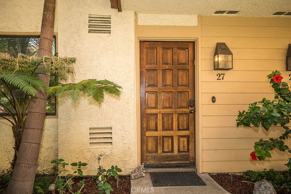 Front view of a house entrance with a wooden door and exterior light fixtures.