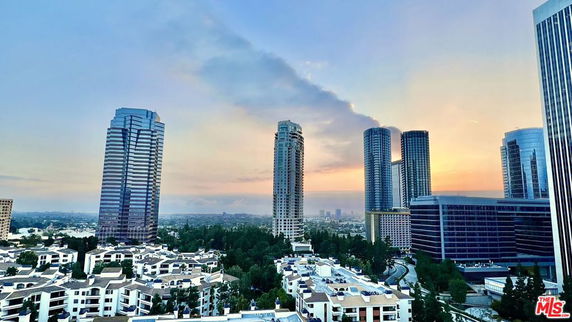 Panoramic view of a cityscape with tall buildings at sunset.