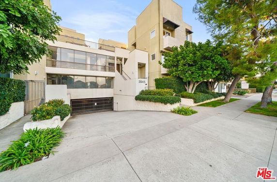 Front view of a modern multi-story building with large windows and landscaped area.