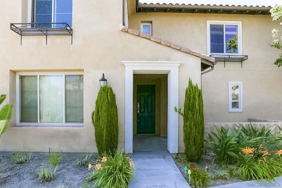 Front view of a two-story house with beige walls and a green front door.