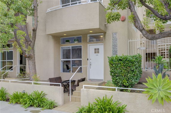 Front view of a modern multi-story building with a small patio area.